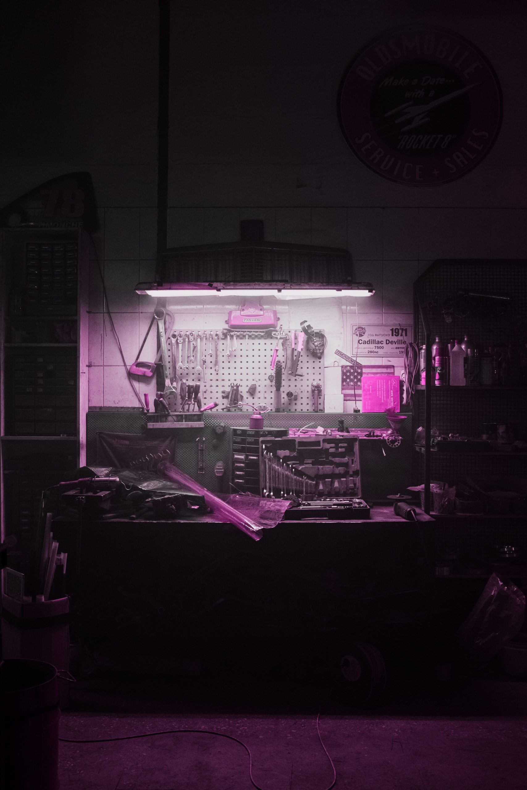 Pink filtered workbench in a dark room with light overhead - female electrician NB